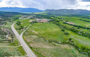 Rural commercial property in Colorado featuring green fields, a small township, and distant mountains.